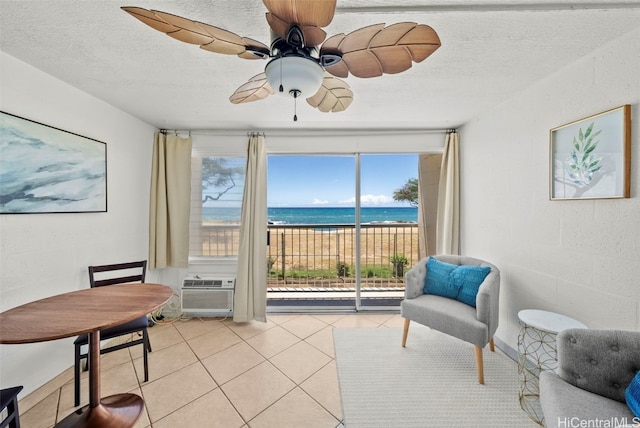 sitting room featuring a textured ceiling, light tile patterned floors, a healthy amount of sunlight, and a water view