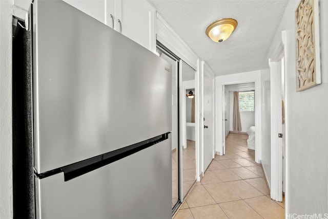 corridor featuring a textured ceiling and light tile patterned flooring