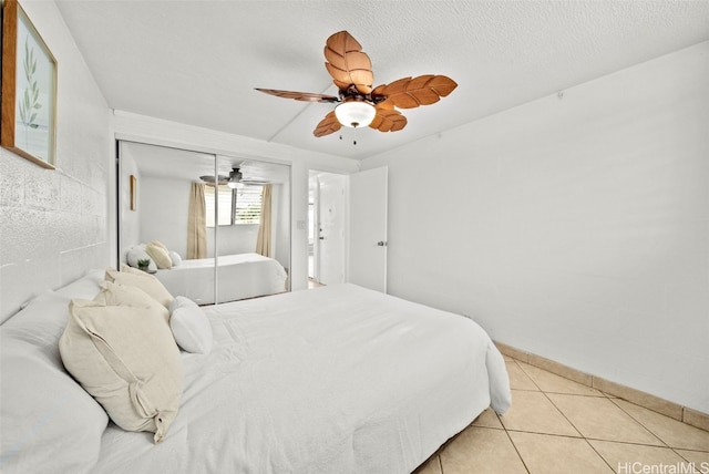 tiled bedroom with ceiling fan, a textured ceiling, and a closet