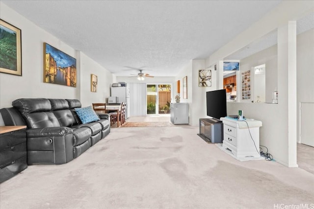 living room featuring ceiling fan, light carpet, and a textured ceiling