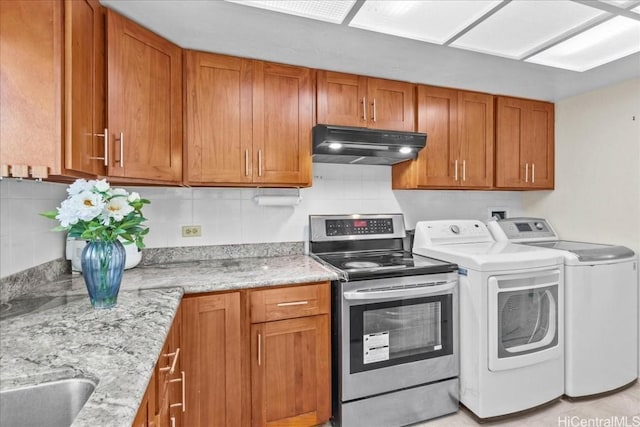 kitchen with tasteful backsplash, light stone countertops, independent washer and dryer, and electric stove