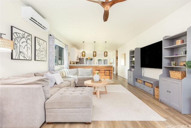 living room featuring light wood-type flooring, ceiling fan, and a wall mounted AC