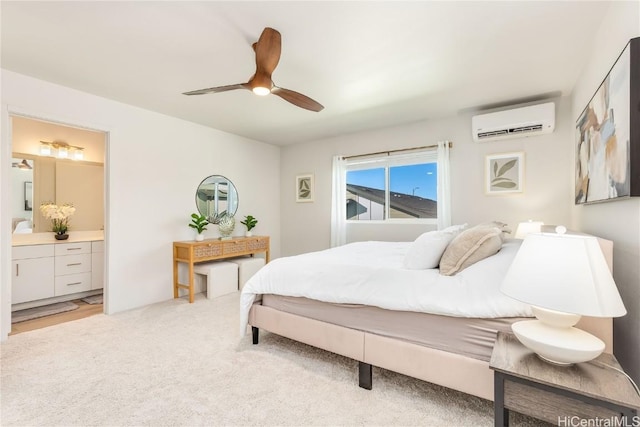 bedroom featuring an AC wall unit, light colored carpet, ensuite bath, and ceiling fan