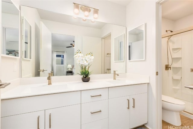 bathroom featuring toilet, a shower with door, ceiling fan, wood-type flooring, and vanity