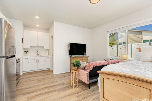 bedroom with light wood-type flooring, sink, and stainless steel refrigerator