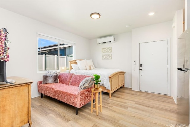 bedroom featuring light hardwood / wood-style floors, stainless steel fridge, and a wall unit AC