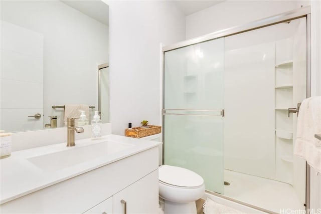 bathroom featuring a shower with shower door, toilet, and vanity