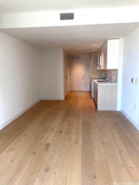 kitchen featuring sink, light hardwood / wood-style flooring, and white cabinets