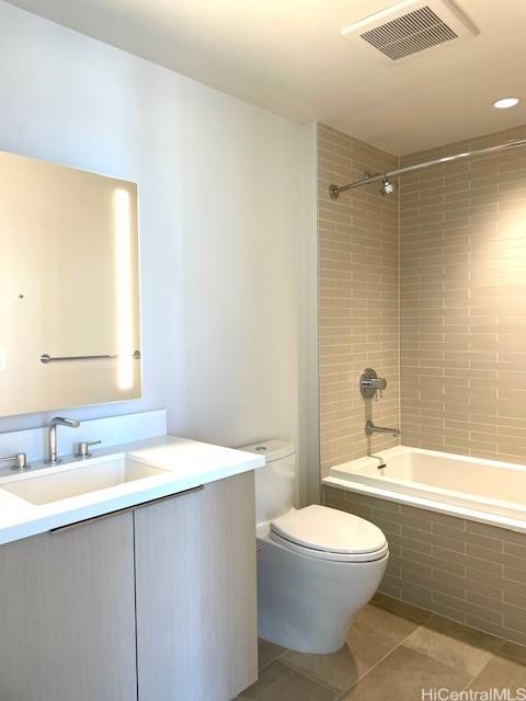 full bathroom with tile patterned flooring, vanity, tiled shower / bath combo, and toilet