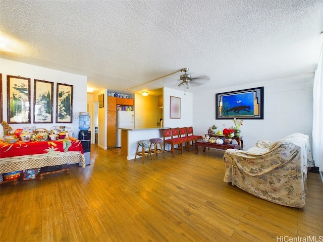 living room featuring ceiling fan, a textured ceiling, and light hardwood / wood-style floors