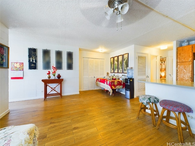 living room featuring ceiling fan, a textured ceiling, and hardwood / wood-style flooring