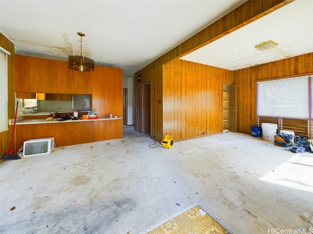 unfurnished living room featuring wood walls and a notable chandelier