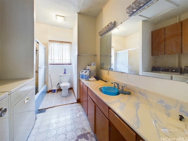 full bathroom with toilet, washer and clothes dryer, vanity, and shower / bath combination with glass door