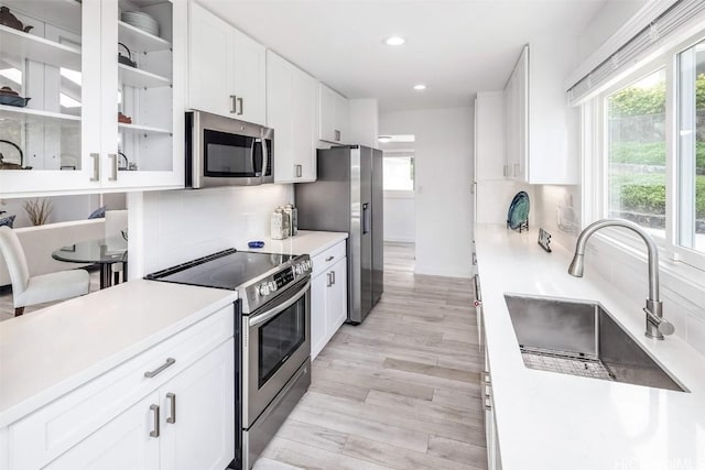 kitchen with stainless steel appliances, white cabinetry, sink, and tasteful backsplash