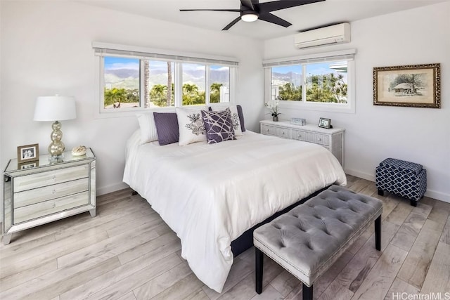 bedroom featuring an AC wall unit, ceiling fan, and light wood-type flooring