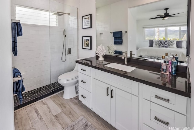 bathroom with vanity, ceiling fan, toilet, and a tile shower