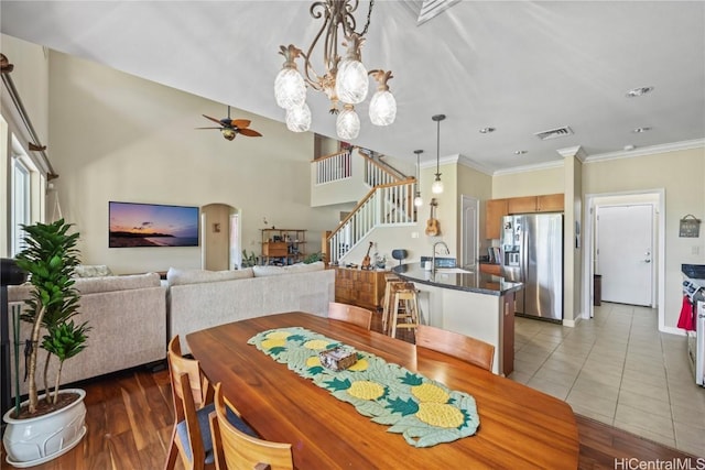 dining space featuring sink, ceiling fan with notable chandelier, ornamental molding, and light tile patterned flooring