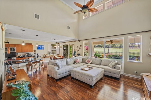 living room featuring dark wood-type flooring, ceiling fan, and ornamental molding