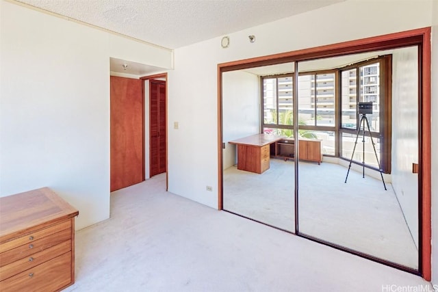 unfurnished bedroom featuring light carpet, a textured ceiling, and a closet