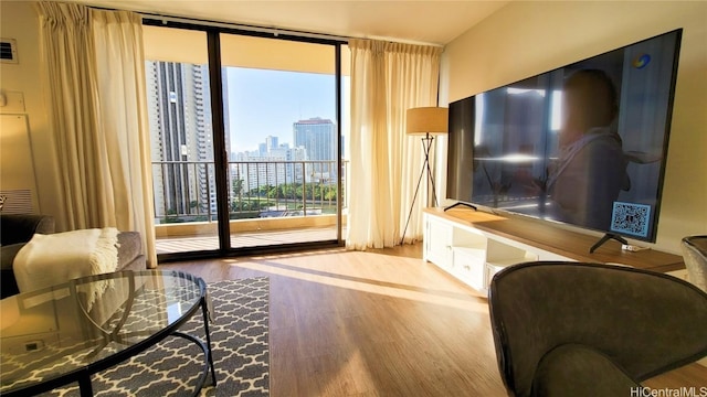 living room featuring a wall of windows, plenty of natural light, and hardwood / wood-style flooring