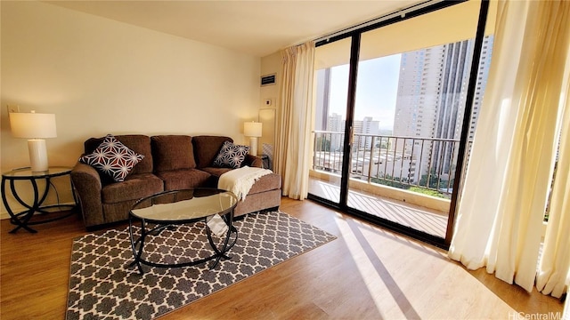 living room featuring a wall of windows, a view of city, and wood finished floors