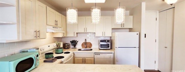 kitchen featuring white appliances, under cabinet range hood, light countertops, and a sink