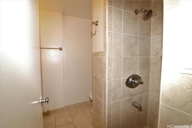 bathroom with toilet, a tile shower, and tile patterned flooring