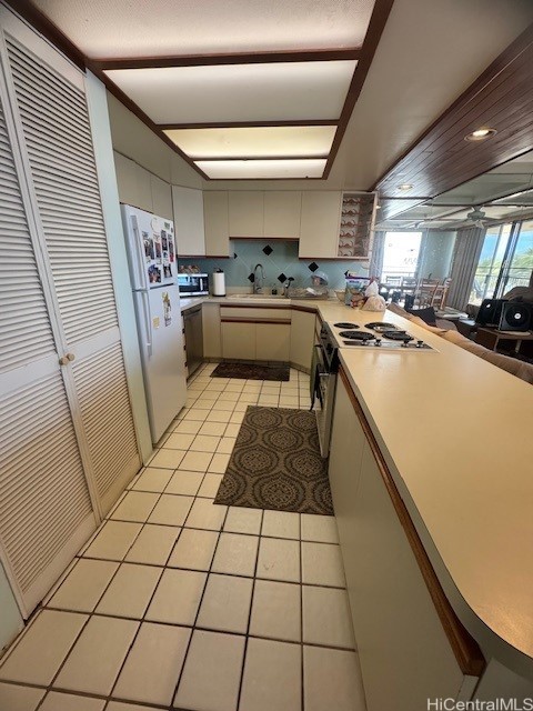 kitchen featuring light tile patterned floors, cream cabinetry, stainless steel appliances, tasteful backsplash, and sink