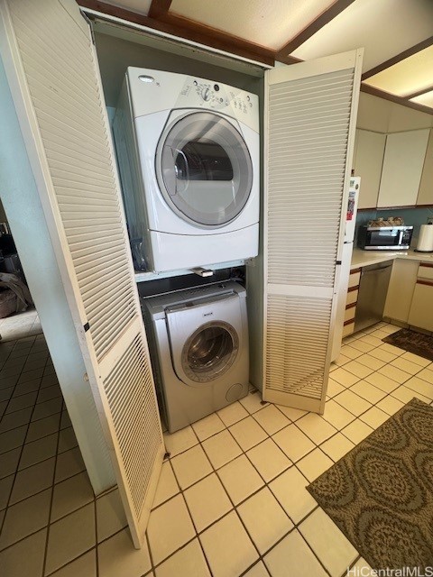 washroom with stacked washer / drying machine and light tile patterned flooring