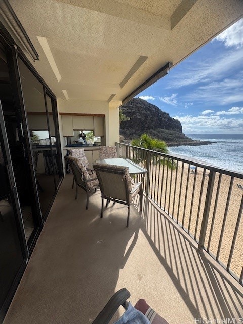 balcony featuring a water view and a beach view