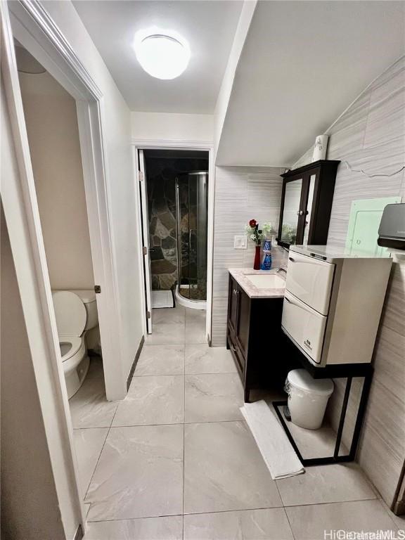 bathroom featuring toilet, vanity, tile walls, and walk in shower