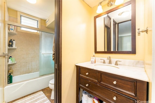 full bathroom with combined bath / shower with glass door, vanity, and toilet