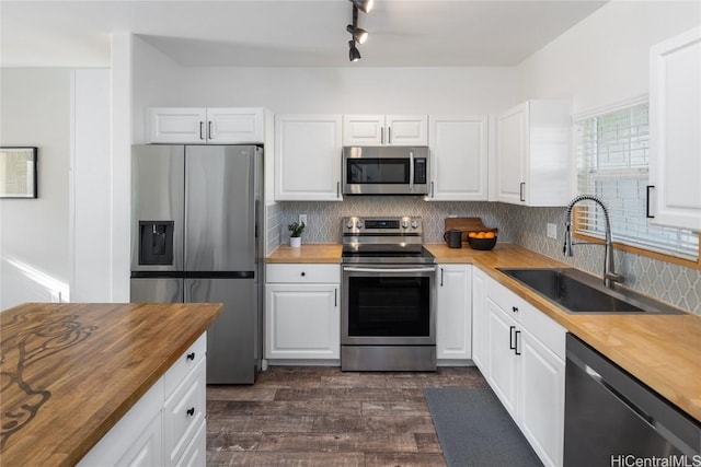 kitchen with sink, stainless steel appliances, white cabinetry, and wooden counters