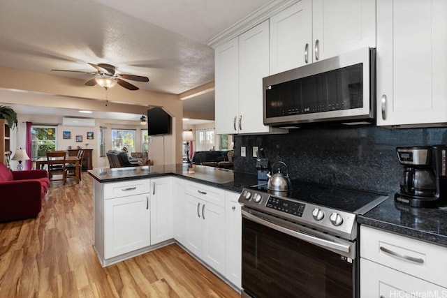 kitchen featuring a textured ceiling, appliances with stainless steel finishes, white cabinetry, decorative backsplash, and a wall unit AC