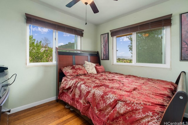 bedroom with ceiling fan, multiple windows, and wood-type flooring