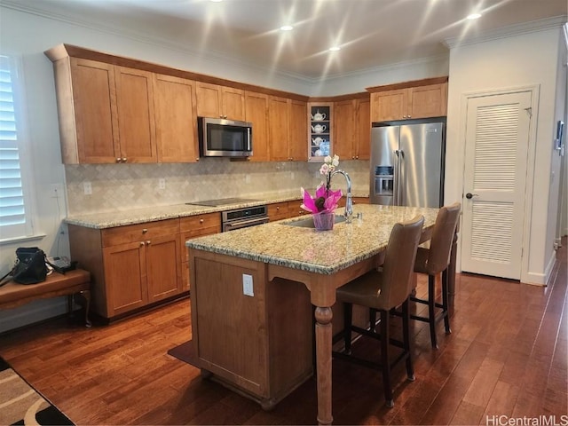 kitchen featuring an island with sink, appliances with stainless steel finishes, sink, and dark wood-type flooring