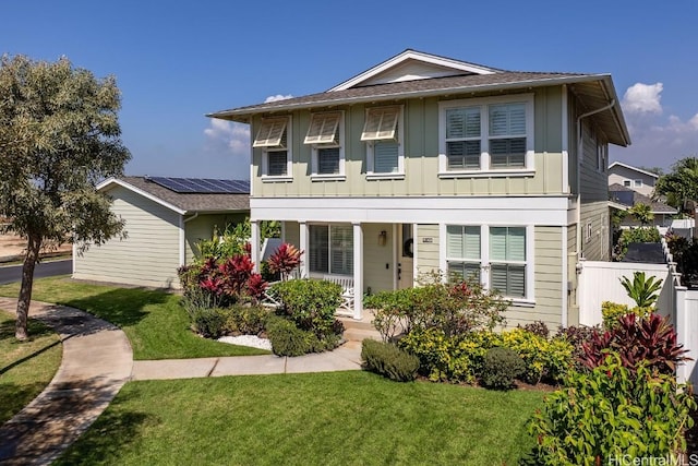 view of front of house featuring covered porch, fence, board and batten siding, and a front yard