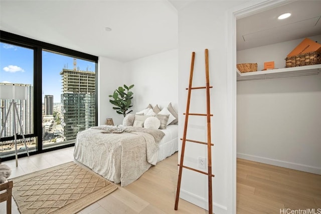 bedroom featuring light wood-type flooring and floor to ceiling windows