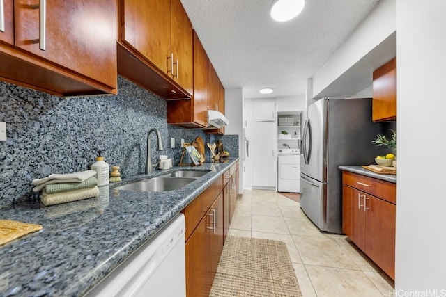 kitchen featuring washer / clothes dryer, tasteful backsplash, sink, stainless steel refrigerator, and light tile patterned floors