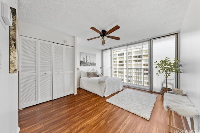 unfurnished bedroom featuring ceiling fan, access to outside, floor to ceiling windows, hardwood / wood-style floors, and a textured ceiling