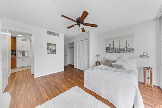 bedroom featuring a closet, ceiling fan, a textured ceiling, and wood-type flooring