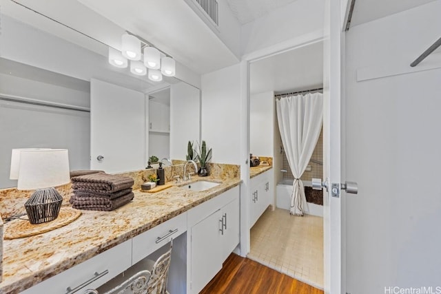 bathroom featuring hardwood / wood-style floors, vanity, and shower / bath combo