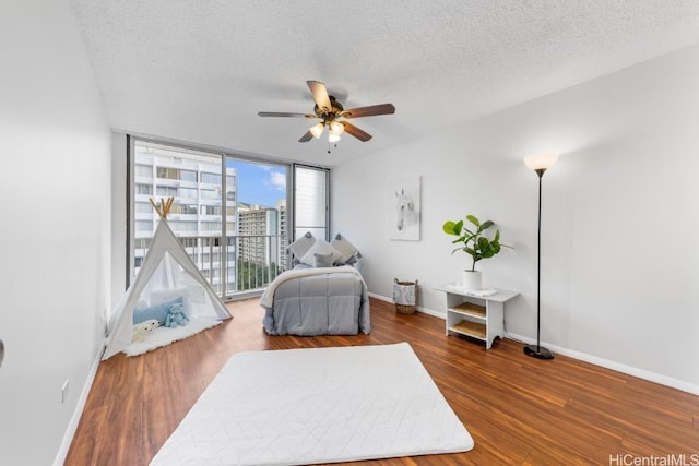 bedroom with dark wood-type flooring, a textured ceiling, a wall of windows, and ceiling fan