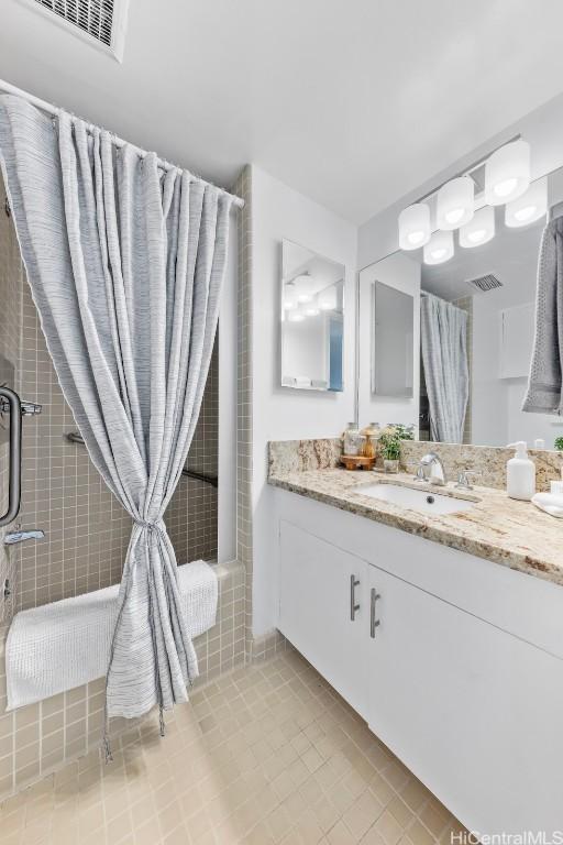 bathroom with tile patterned flooring, walk in shower, and vanity