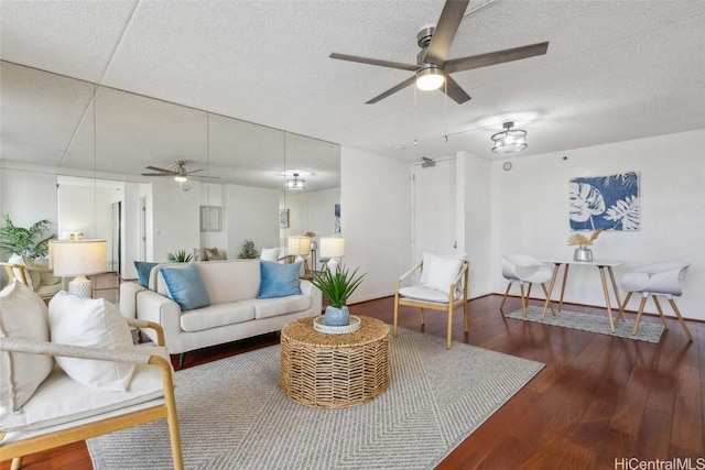 living room with a textured ceiling, dark wood-type flooring, and ceiling fan