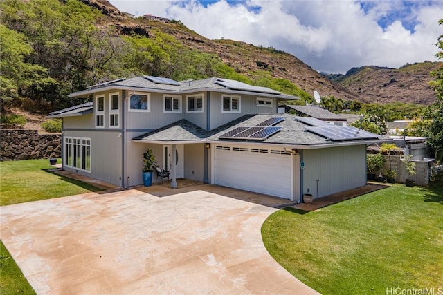 view of front facade with a mountain view, a garage, a front lawn, and solar panels