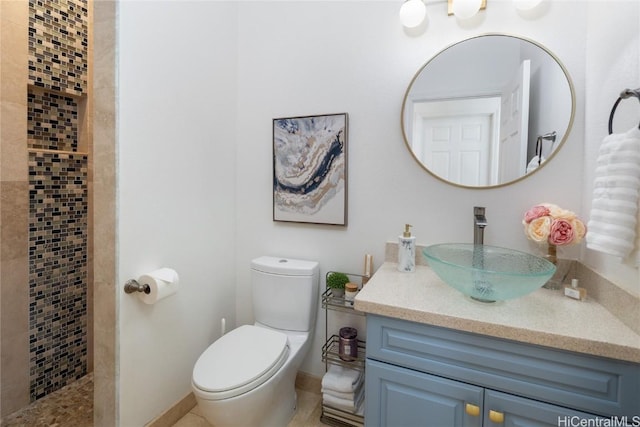 bathroom featuring vanity, a tile shower, and toilet