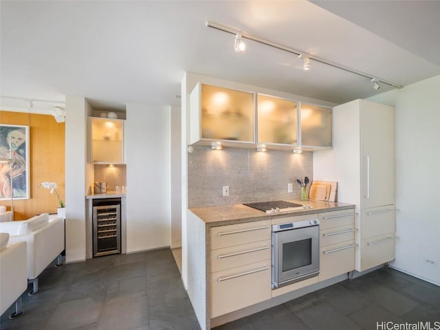 kitchen featuring tasteful backsplash, wine cooler, rail lighting, oven, and black electric cooktop