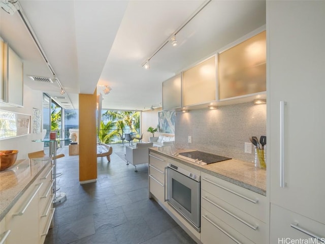 kitchen with white cabinets, oven, light stone counters, and black electric cooktop