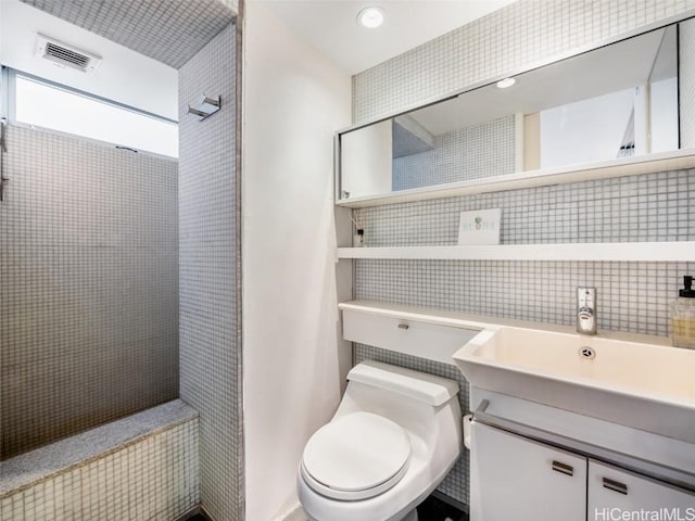 bathroom featuring backsplash, toilet, vanity, and a shower